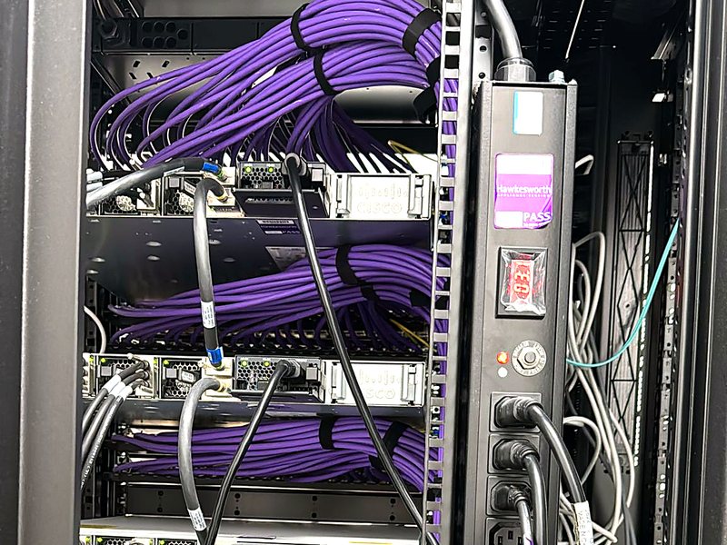 Data centre cabinet with bundled purple network cables and a rack power distribution unit