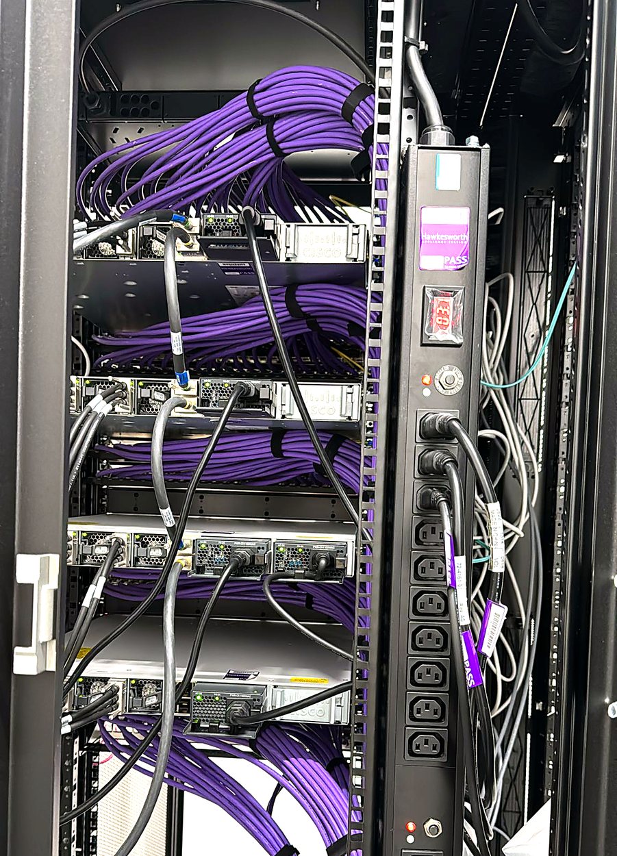 Data centre cabinet with bundled purple network cables and a rack power distribution unit