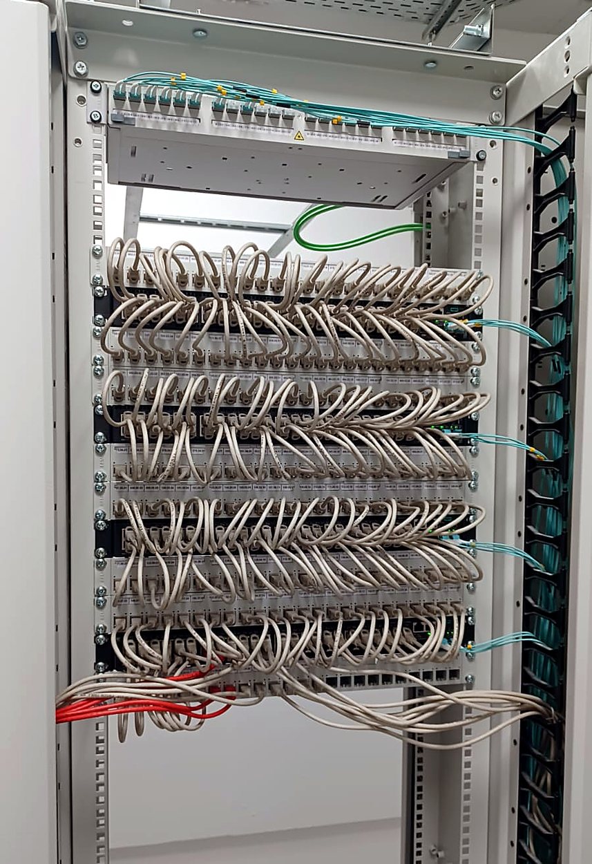 Rack cabinet with patch panels and dressed grey patch cords and fibre uplinks