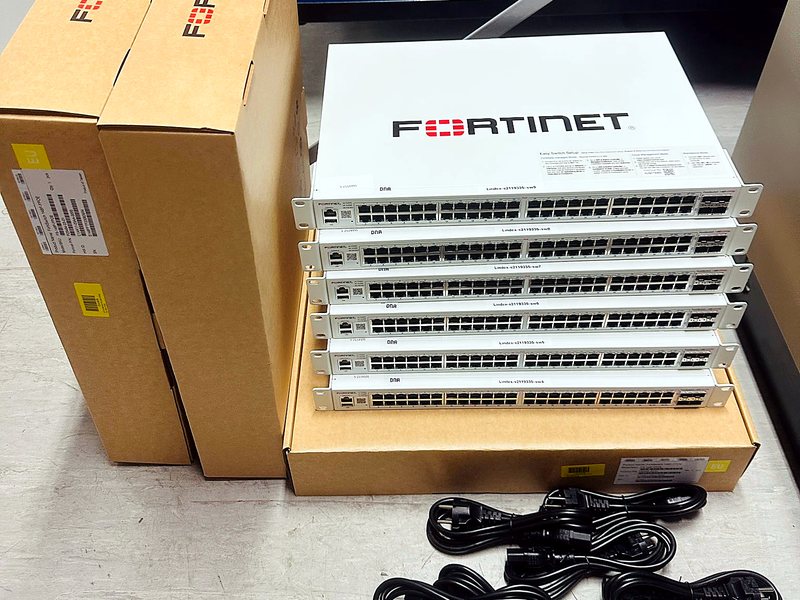 Stack of Fortinet network switches unboxed with power cables ready for rack installation