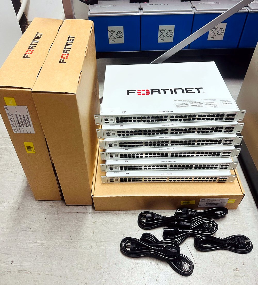 Stack of Fortinet network switches unboxed with power cables ready for rack installation